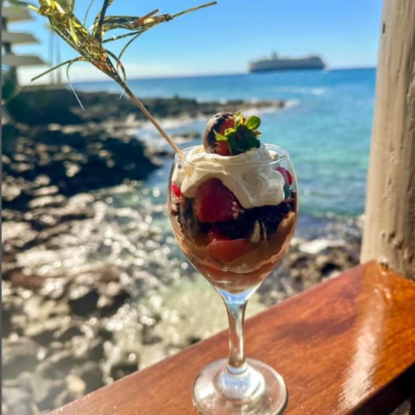 A Kai Eats + Drinks dessert trifle with whipped cream and strawberries, overlooking the ocean.
